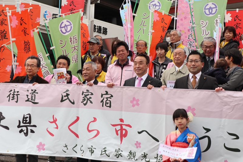「栃木県さくら市へようこそ」という垂れ幕を持つ市長と関係者の写真