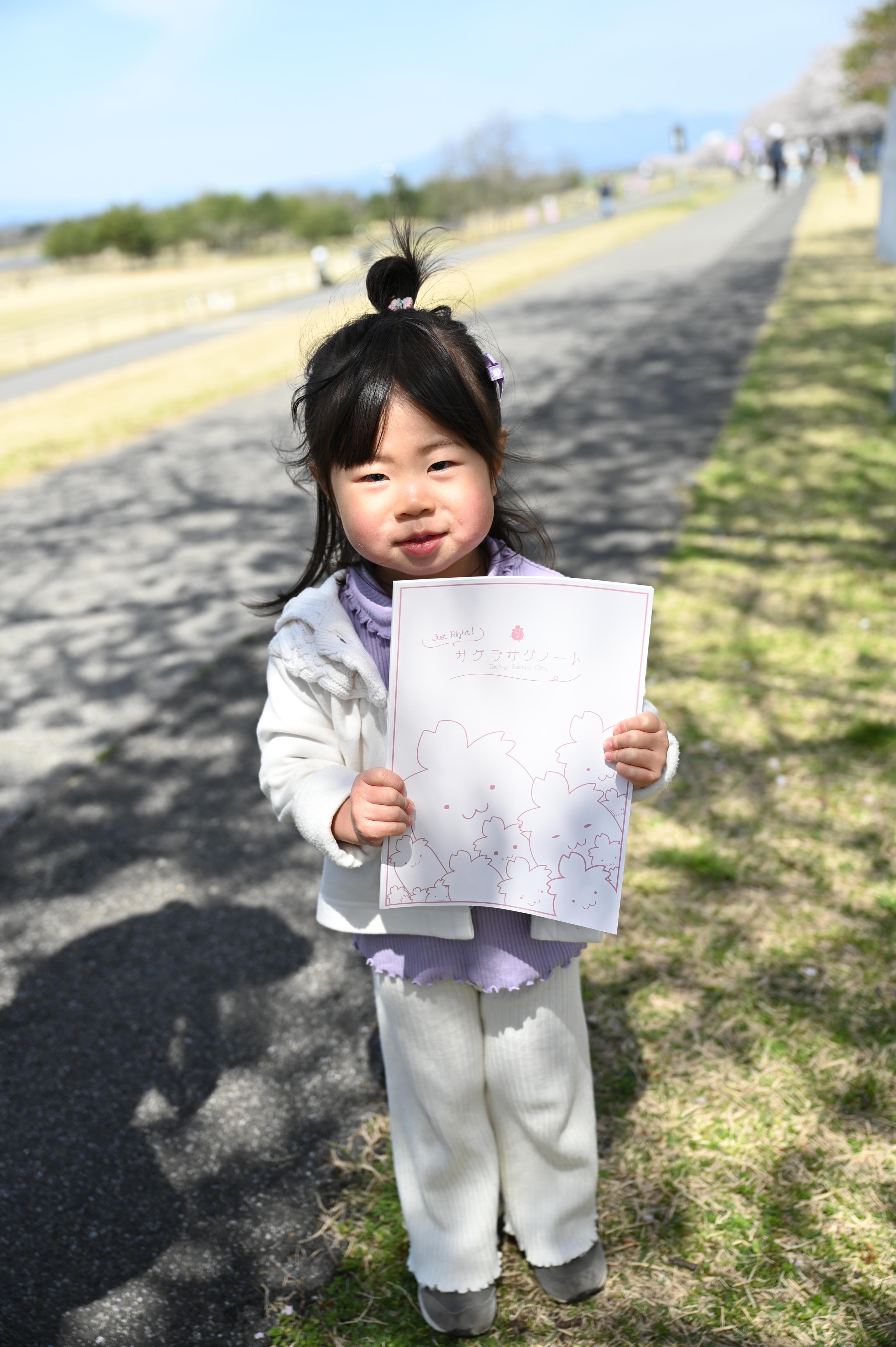 サクラサクノートを掲げる女の子の写真